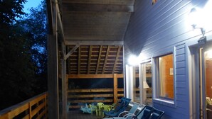 A wooden deck with lounge chairs and a covered area with a sloped ceiling.