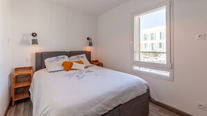 A bedroom with a bed, two bedside tables, a window, and a hanging light fixture. - Bright, Newly Renovated Apartment with Wi-Fi and Air Conditioning (Sanary-sur-Mer)