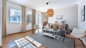 A spacious living area with a sofa, coffee table, and wicker chair, large windows with curtains, and a hanging light fixture. - Apartment 'Penthouse In Old Town' with Panoramic Sea and Mountain Views, Wi-Fi and Air Conditioning (Fuengirola)