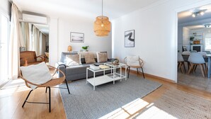 A modern living room with a sofa, coffee table, and chairs, a dining area with a table and chairs, and a kitchen visible through an open door. - Apartment 'Penthouse In Old Town' with Panoramic Sea and Mountain Views, Wi-Fi and Air Conditioning (Fuengirola)