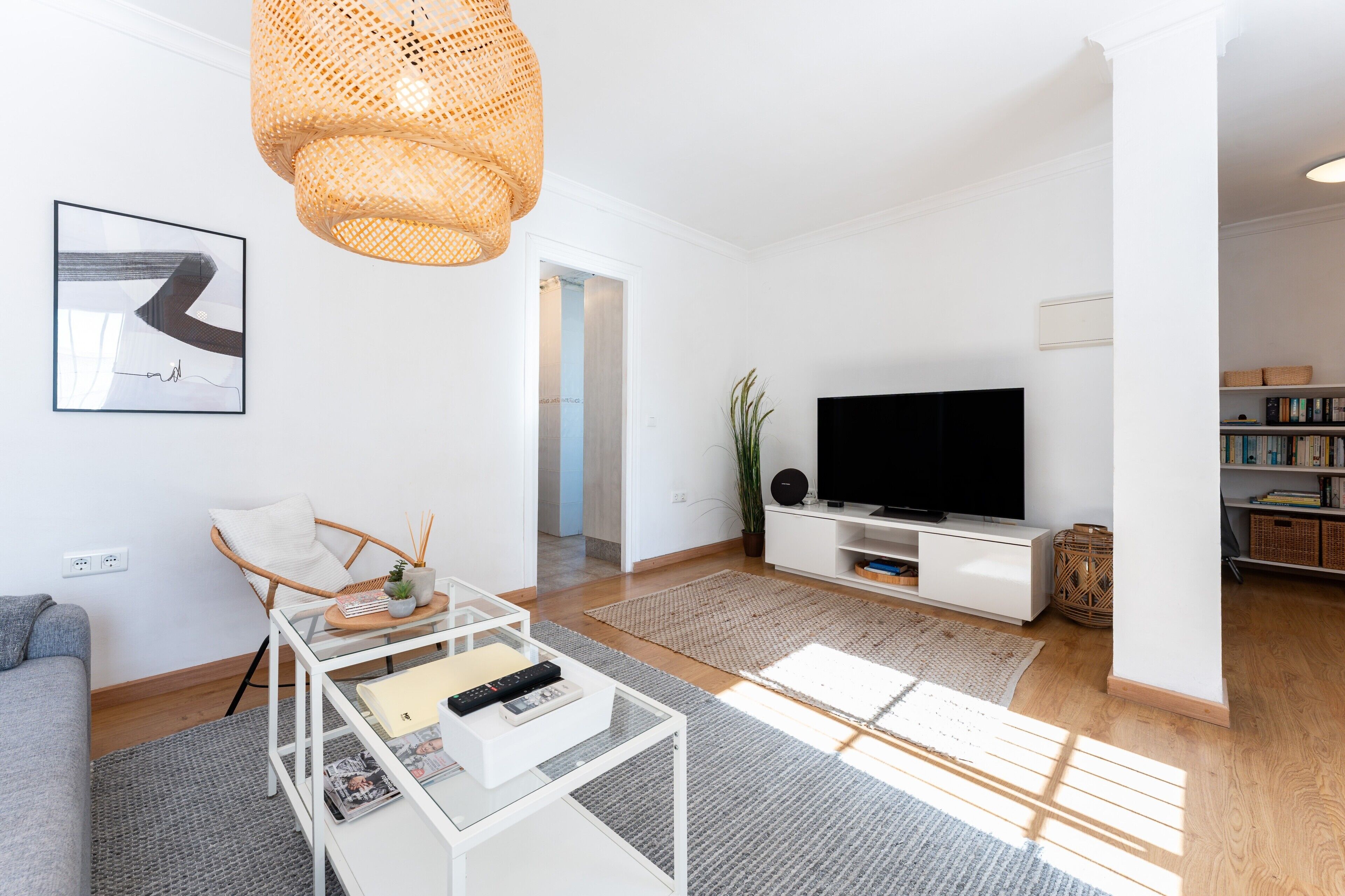 Uma sala de estar moderna com sofá, mesa de centro, televisão e estante.