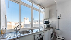A modern kitchen with a large window, a washing machine, and a microwave. - Apartment 'Penthouse In Old Town' with Panoramic Sea and Mountain Views, Wi-Fi and Air Conditioning (Fuengirola)