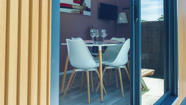 A modern interior with a dining area, a television mounted on the wall, and a sliding glass door leading to an outdoor space. - La tiny T Loches, close to Beauval Zoo and the Châteaux. (Loches)