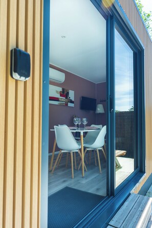 A modern interior with a dining area, a television mounted on the wall, and a sliding glass door leading to an outdoor space. - La tiny T Loches, close to Beauval Zoo and the Châteaux. (Loches)