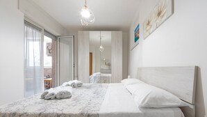 A bedroom with a bed, a nightstand, a mirror, and a window with a view. - Apartment 'Di Titina' with Private Terrace and Air Conditioning (Otranto)