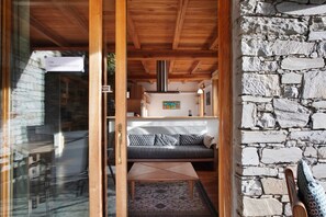 A wooden ceiling, a stone wall, a sofa, and a table with a patterned rug.