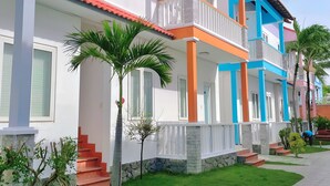 A multi-story residential building with a red-tiled roof, white walls, and balconies. - Volga Hotel Mui Ne (Mui Ne)