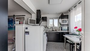 A compact kitchen with a washing machine, a microwave, and a dining area with a table and chairs. - Chez Brigitte – Charming Studio in Audenge with Terrace, Bikes, and Close to Bassin d'Arcachon (Audenge)