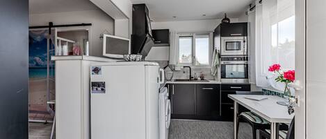 A compact kitchen with a washing machine, a microwave, and a dining area with a table and chairs.