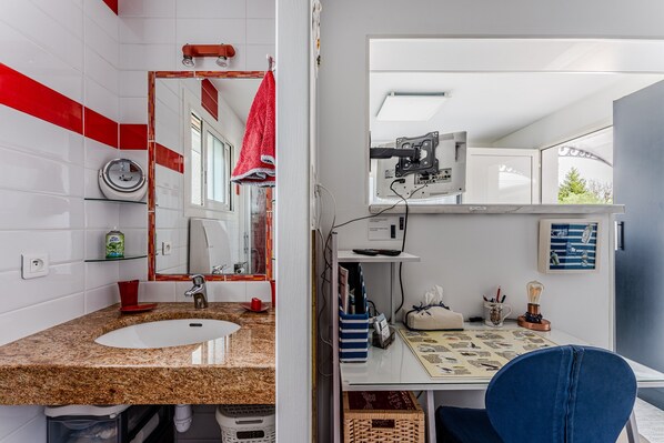 A bathroom with a sink, mirror, and red towel hanging on the wall.