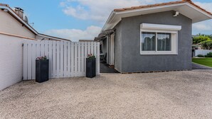 A modern house with a grey exterior, white window frames, and a gravel driveway. - Chez Brigitte – Charming Studio in Audenge with Terrace, Bikes, and Close to Bassin d'Arcachon (Audenge)
