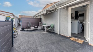 A residential property with a patio, outdoor seating, a washing machine, and a bicycle. - Chez Brigitte – Charming Studio in Audenge with Terrace, Bikes, and Close to Bassin d'Arcachon (Audenge)