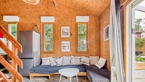 Une pièce chaleureuse avec un plafond en bois, un canapé, une petite table et un réfrigérateur.