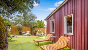 Un bâtiment rouge avec deux fauteuils en bois et une petite table dans la cour.