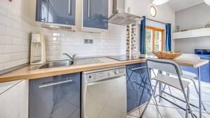 Een moderne keuken met een vaatwasser, spoelbak en een raam met blauwe gordijnen.