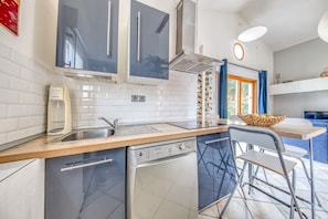 A modern kitchen with a dishwasher, sink, and a window with blue curtains.