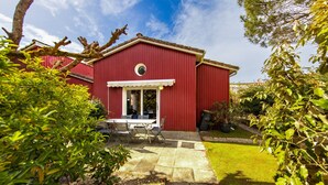 Een rood gebouw met een overdekte patio, een kleine tafel en stoelen, en een gazon.
