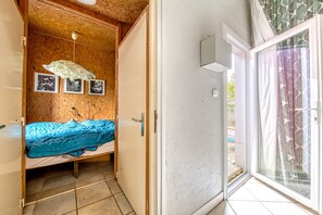 Una habitación con cama, techo de madera, una puerta y un ventanal con cortina.