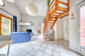Una sala de estar moderna con un sofá azul, una escalera de madera y un comedor con mesa.