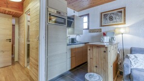 A kitchen with wooden cabinets, a built-in oven, and a dining area with a table and chairs.