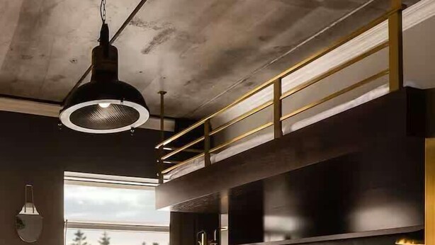 Une chambre moderne avec un grand lit, une tête de lit noire à motifs et une fenêtre donnant sur la forêt.