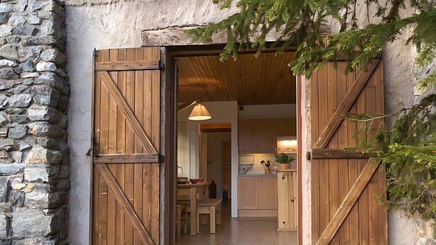 Een rustiek stenen gebouw met houten deuren en een zichtbare keuken.