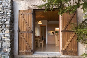 Un bâtiment rustique en pierre, doté de portes en bois et d’une cuisine visible.