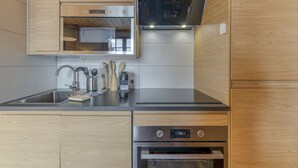 Een moderne keuken met houten kastjes, een roestvrijstalen spoelbak en inbouwapparatuur, zoals een oven en een magnetron.