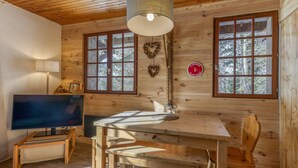 Een houten cabin met een televisie, een houten tafel, stoelen, een raam en een bordje aan de muur.