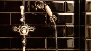 Ein Badezimmer im Vintage-Stil mit einer klassischen Dusche und einem an der Wand befestigten Wasserhahn.