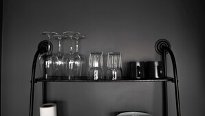 A black metal shelf with wine glasses, a roll of toilet paper, and a bowl. - Urban Reykjavik Top Floor Studio (Reykjavík)