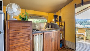 Een kleine keuken met een ventilator, een spoelbak en uitzicht op de omgeving.