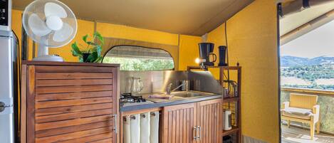 A compact kitchen with a fan, a sink, and a view of the outdoors.