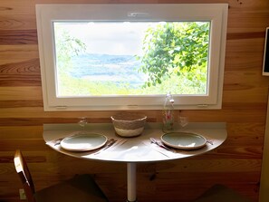 A dining table with two plates, a bowl, and a wine glass.