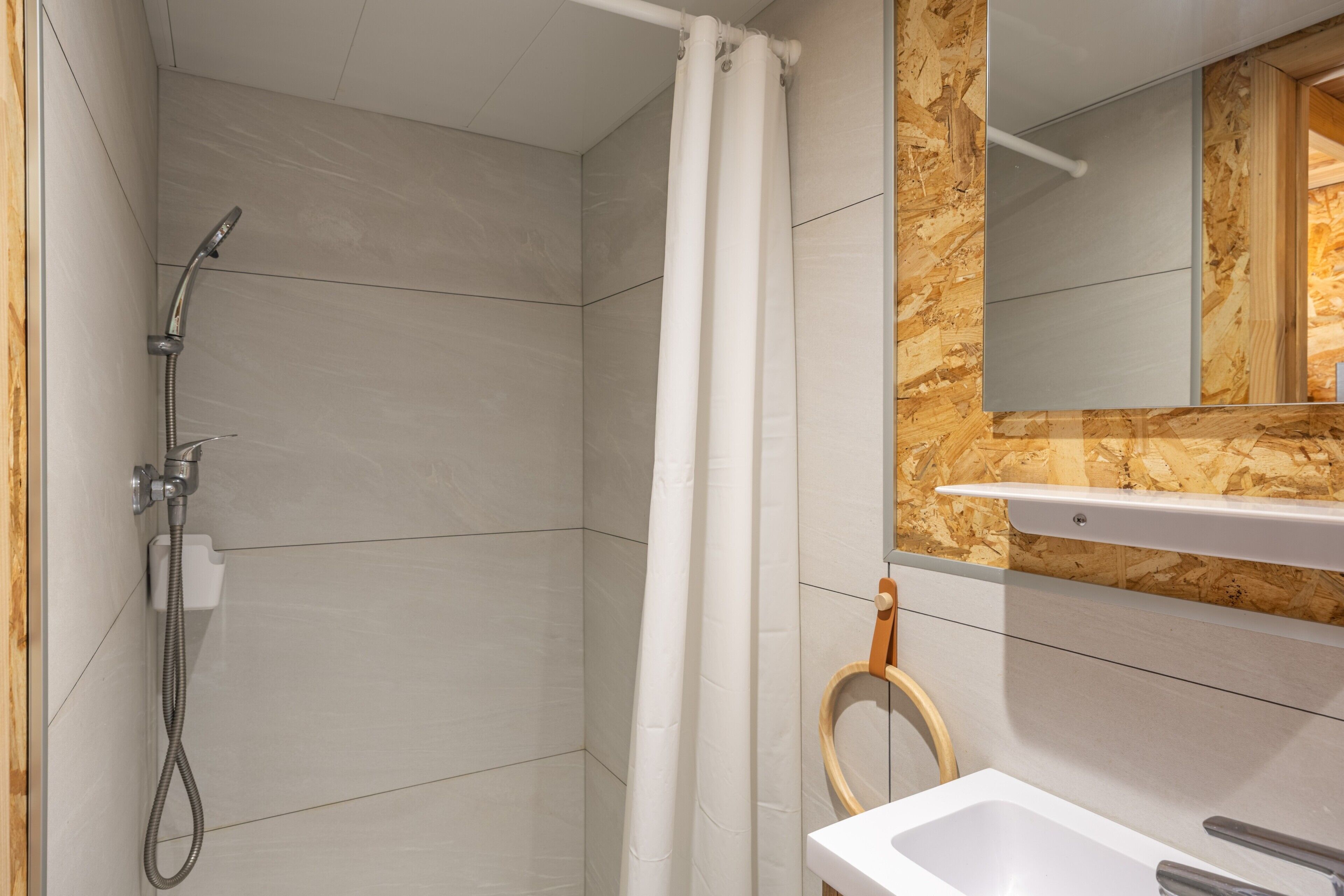 A bathroom with a shower, a sink, and a mirror.
