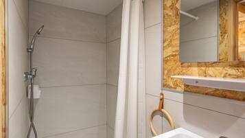 A bathroom with a shower, a sink, and a mirror.