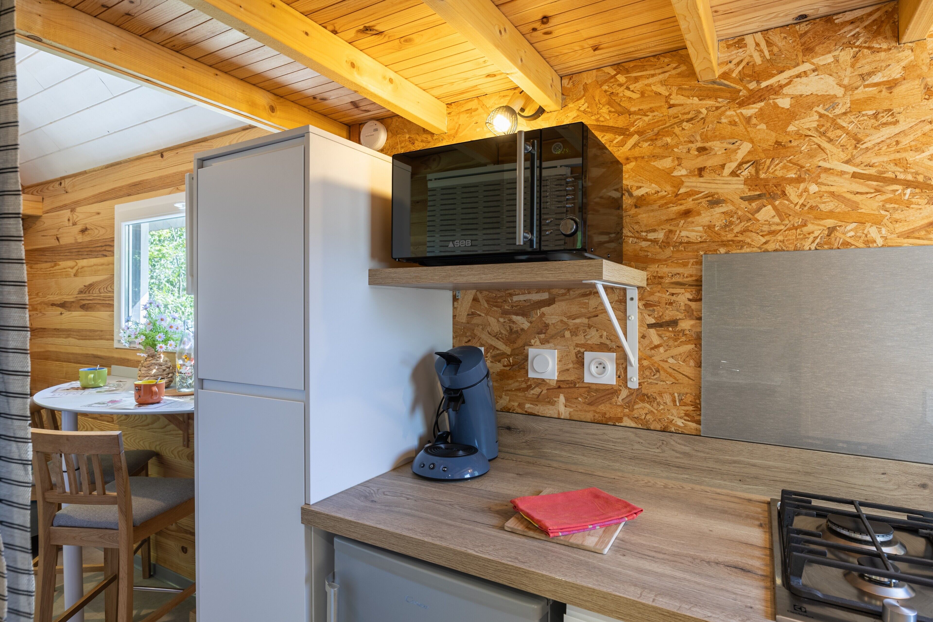 A compact kitchen with a microwave, coffee maker, and a gas stove.
