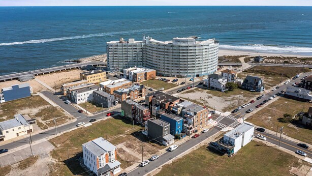 Vue aérienne d’une zone côtière comprenant un grand complexe hôtelier, des routes et une plage.
