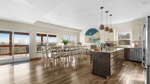 Une cuisine spacieuse dotée d’un grand îlot central, d’un plancher en bois et offrant une vue sur l’extérieur.