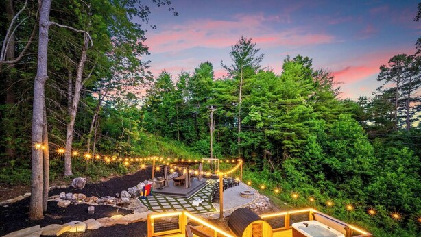 A wooden deck with a hot tub, seating area, and string lights.