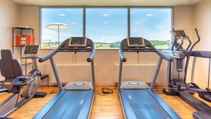 Un gimnasio con cintas de correr, elípticas y una máquina de remo.