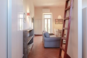 A living room with a sofa, a wooden ladder, and a radiator. - Holiday Home 'Frantoio 4 Superior' with Shared Pool, Wi-Fi and Air Conditioning (Cortona)