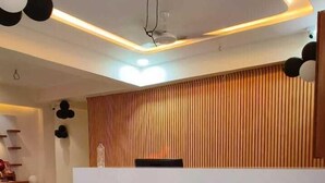 A modern reception area with a wooden reception desk, a ceiling fan, and a marble floor. - Hotel Konark (Ahmedabad)