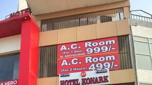 A hotel with a staircase leading to the entrance, signs advertising A.C. rooms, and a closed shuttered entrance. - Hotel Konark (Ahmedabad)