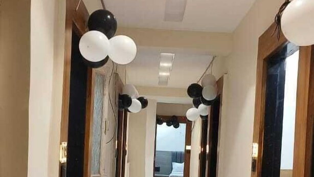A hotel hallway with marble flooring, wooden doors, and pendant lighting. - Hotel Konark (Ahmedabad)