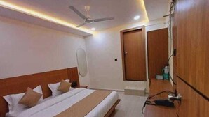 A modern hotel room with a large bed, a ceiling fan, and a wooden wardrobe. - Hotel Konark (Ahmedabad)