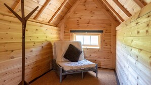 A small, cozy room with wooden walls and a sloped ceiling, featuring a single bed with a pillow and a window providing natural light. - Dartmoor Eco-Pod (Oak Tree Lane) Gorgeous rustic charm (Okehampton)