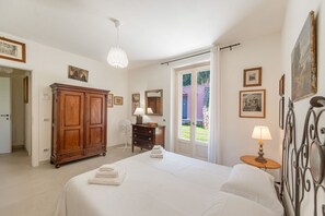 A bedroom with a bed, a wardrobe, a desk, a lamp, and a window with a view.