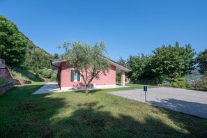 A small pink building with a tree in front, a gravel driveway, and a clear blue sky.