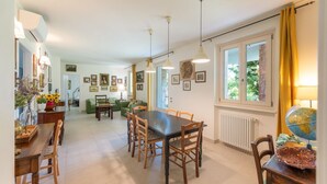 A dining area with a table and chairs, a globe on a side table, and a window with curtains. - ApartmentsGarda - Cottage Capre (GARDA)